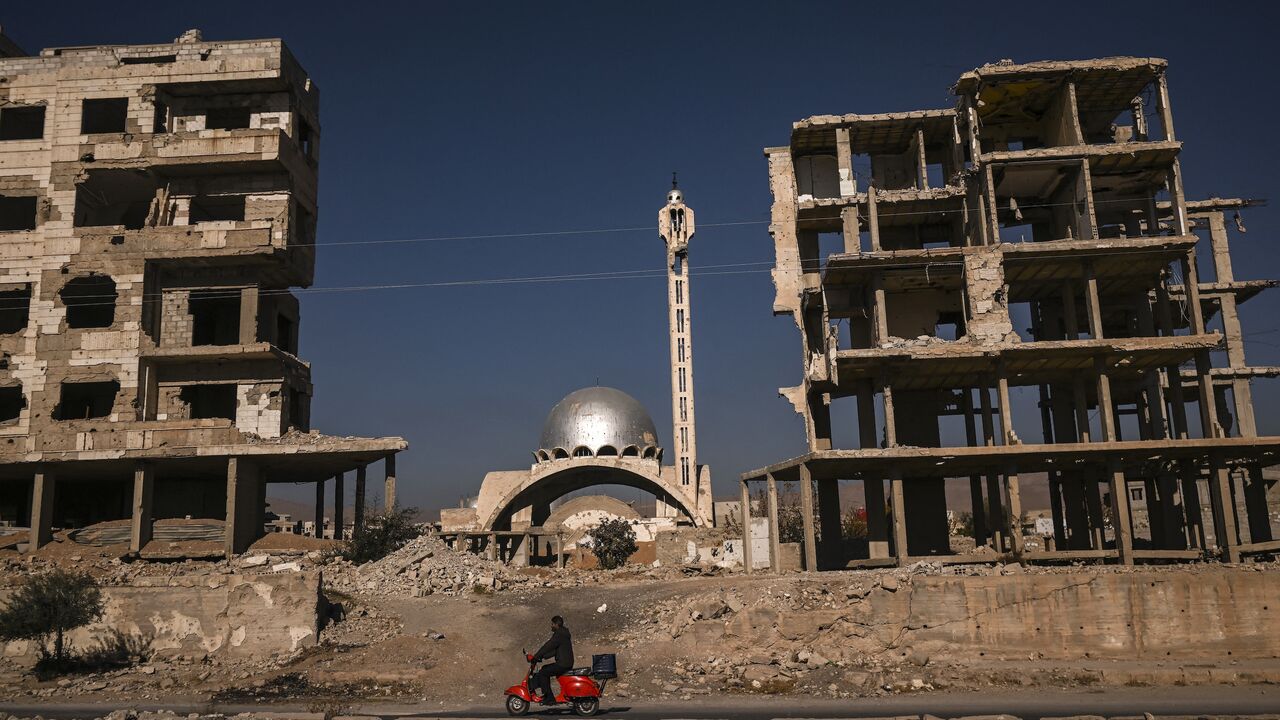 A man rides his scooter past a destroyed mosque and apartment buildings in Harasta, near the Syrian capital, Damascus, on Dec. 19, 2024. 