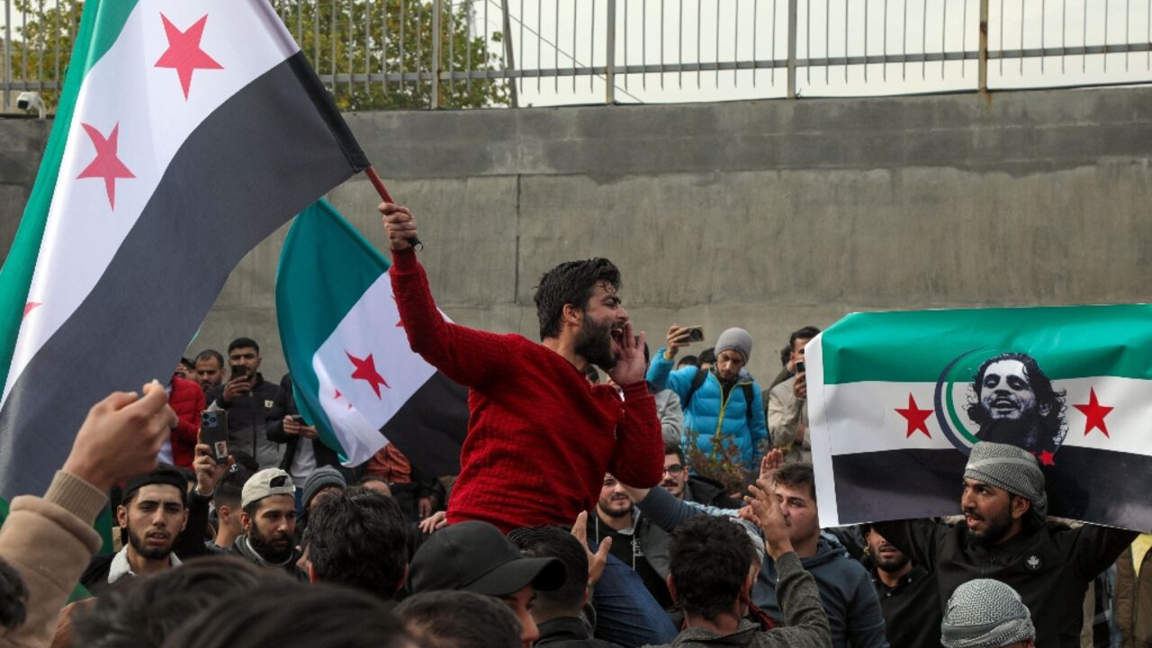 Syrians wave opposition flags, one with the portrait of late rebel fighter Abdel-Basset al-Sarout in Arbil, in the capital of Iraq's northern autonomous Kurdish region, after rebels captured the Syrian capital