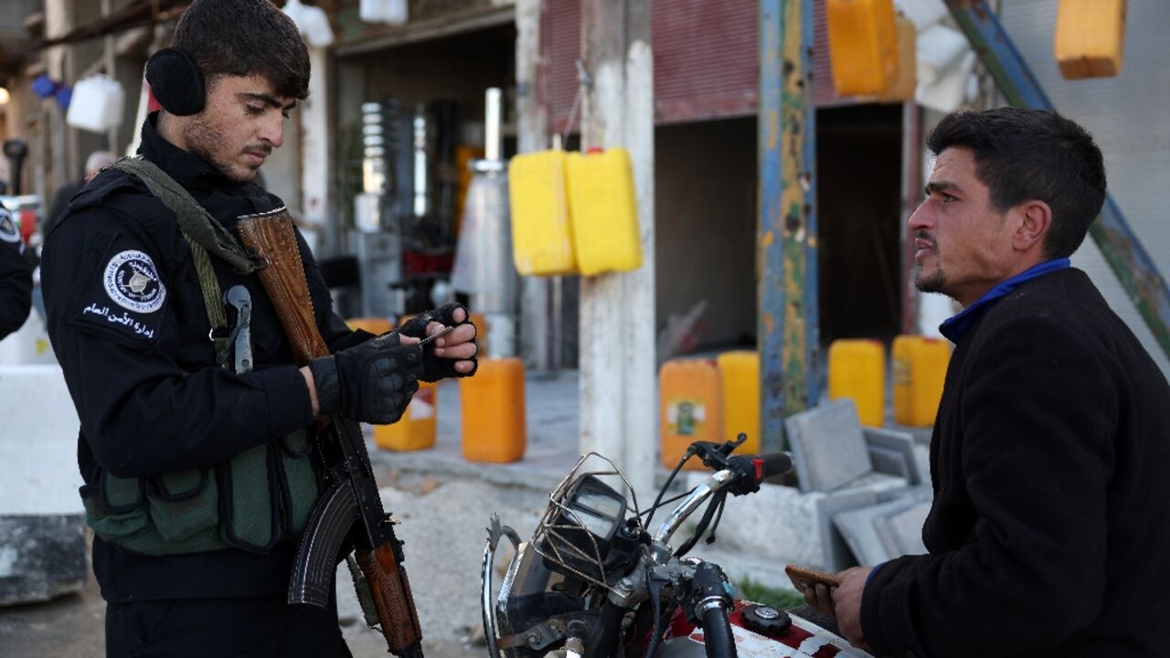 Security forces under Syria's new authorities check the identification of a man in Homs Security forces under Syria's new authorities check the identification of a man in Homs