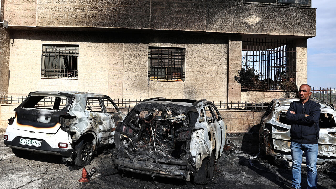 A man stands by burnt vehicles at the site of a reported attack by Israeli settlers in a residential area on the outskirts of Ramallah city in the occupied West Bank, on November 4, 2024. (Photo by Zain JAAFAR / AFP) (Photo by ZAIN JAAFAR/AFP via Getty Images)