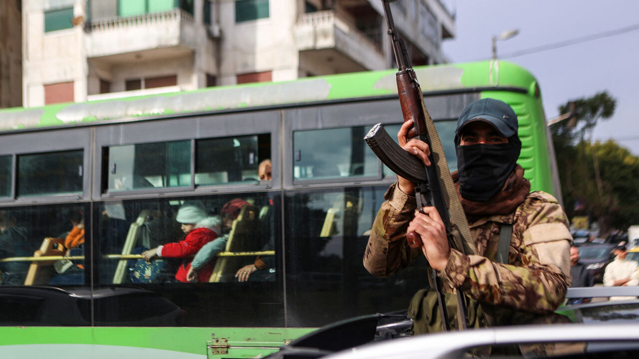 A fighter affiliated with Syria's new administration gestures with his rifle in Syria's western coastal city of Latakia on December 26, 2024. Syria's new authorities launched an operation in a stronghold of ousted president Bashar al-Assad on December 26, with a war monitor saying three gunmen affiliated with the former government were killed, a day after angry protests erupted in several areas around Syria over a video showing an attack on an Alawite shrine that circulated online. (Photo by AAREF WATAD / A