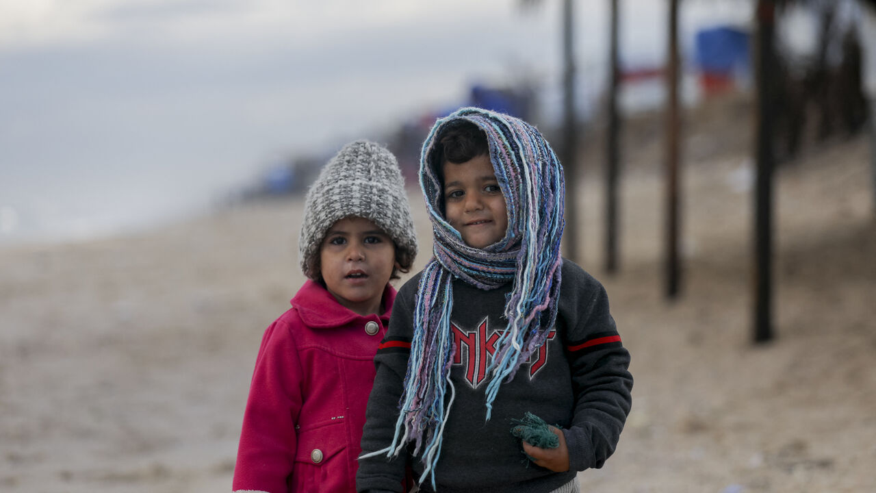 Children stand on a beach in Deir al-Balah, Gaza Strip, on December 30, 2024. The severe storms have caused significant damage to the already fragile living conditions in the camp. (Photo by Youssef Alzanoun / Middle East Images / Middle East Images via AFP) (Photo by YOUSSEF ALZANOUN/Middle East Images/AFP via Getty Images)