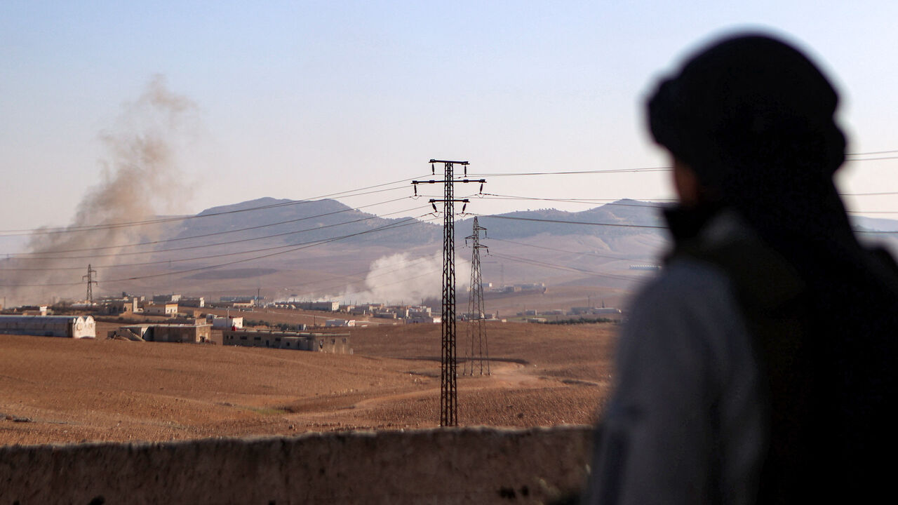 A fighter of the the Turkish-backed Syrian National Army faction watches a plume of smoke erupt from bombardment at a position near the Tishrin Dam in the vicinity of Manbij, in the east of Syria's northern Aleppo province, on January 10, 2025 amidst ongoing battles with the Kurdish-led Syrian Democratic Forces (SDF). The latest reported fighting comes despite the US on December 8 saying that it was working to address Turkey's concerns in Syria to dissuade the NATO ally from escalating an offensive against 