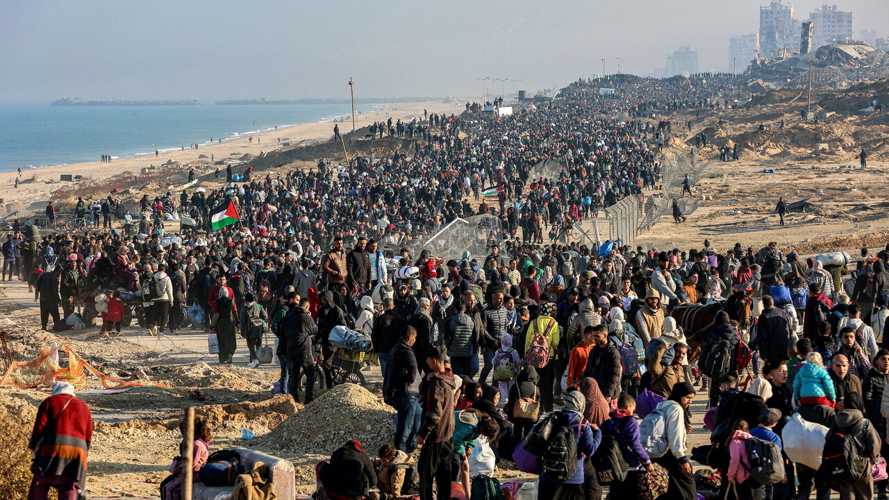 People walk along Gaza's coastal al-Rashid Street to cross the Netzarim corridor from the southern Gaza Strip into the north on Jan. 27, 2025.  