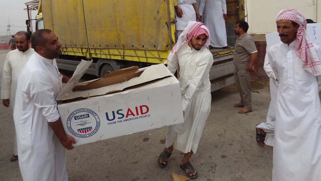 Iraqi men unload humanitarian aid supplies provided by USAID to displaced Iraqis who have fled clashes between Islamic State group jihadists and Peshmerga fighters on Oct. 2, 2014, in the town of Daquq.