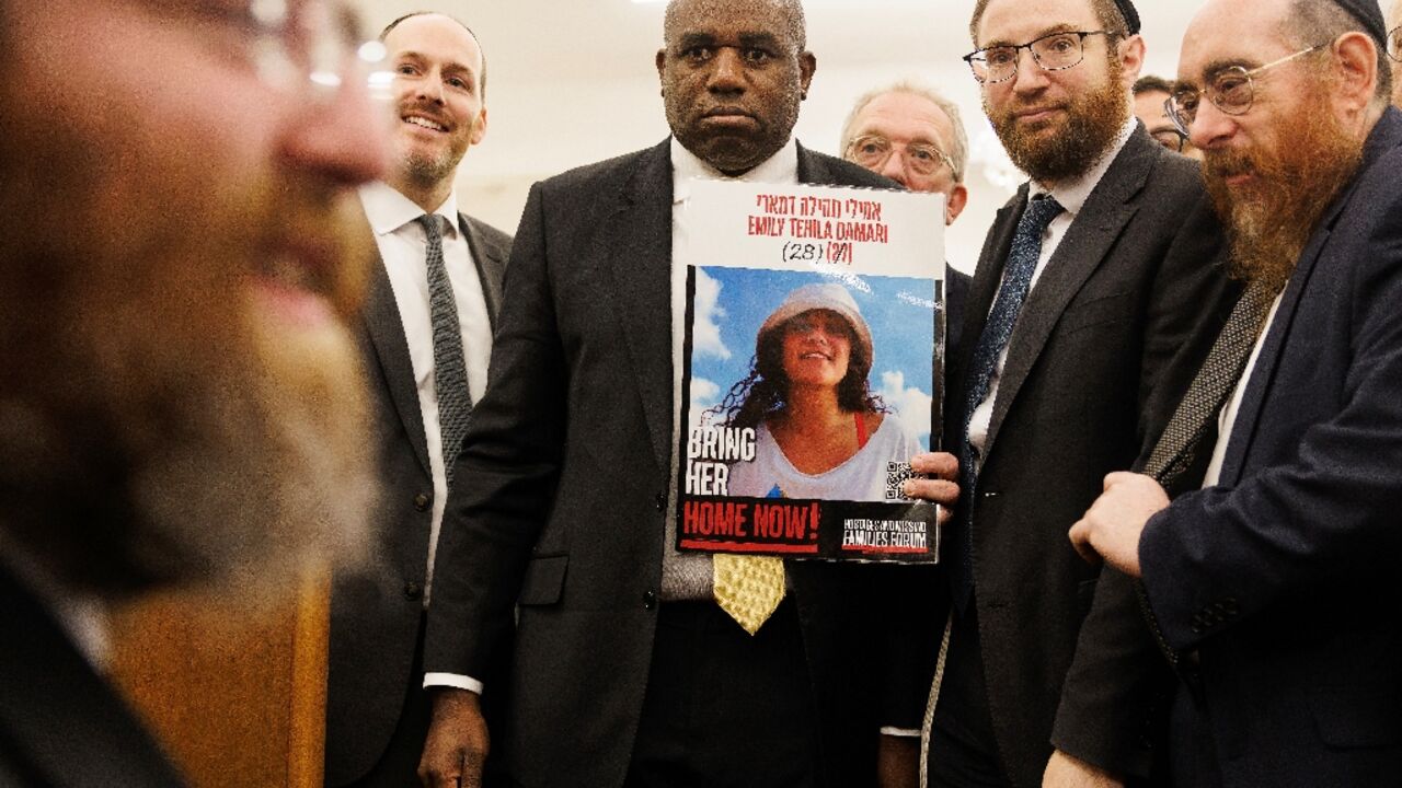 Britain's Foreign Secretary David Lammy holding a poster showing hostage Emily Damari 