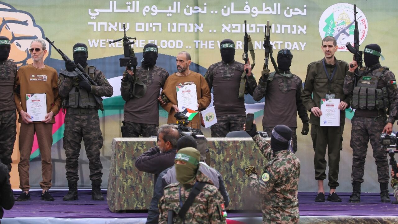 Palestinian Hamas fighters escort Israeli hostages Ohad Ben Ami, Or Levy and Eli Sharabi on a stage before handing them over to a Red Cross team in Deir el-Balah, central Gaza