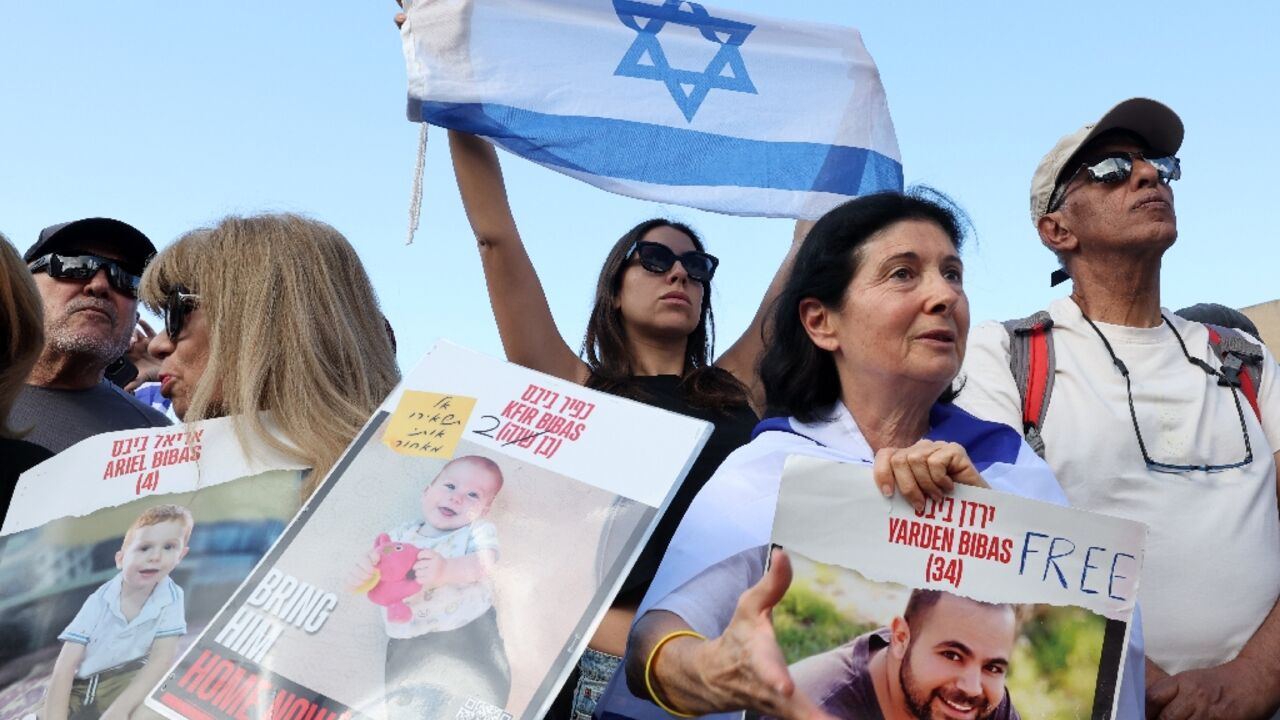 Onlookers with pictures of released hostage Yarden Bibas, as well as of his two children Kfir and Ariel Onlookers with pictures of released hostage Yarden Bibas, as well as of his two children Kfir and Ariel