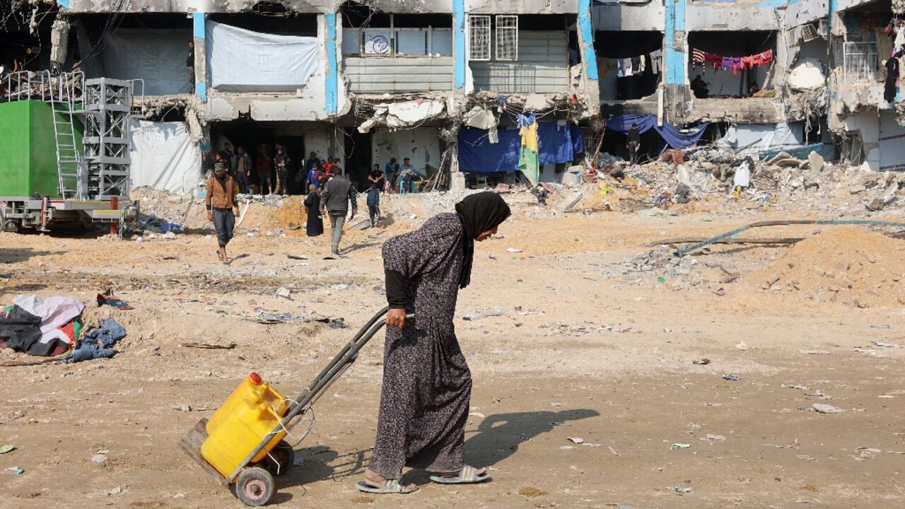 A Palestinian woman pulls a trolley with water cans in Jabalia in the northern Gaza Strip