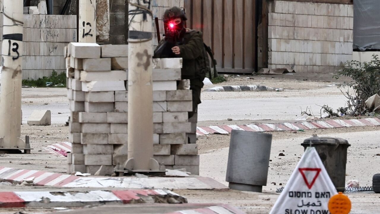 An Israeli soldier takes aim from a checkpoint in the Nur Shams refugee camp