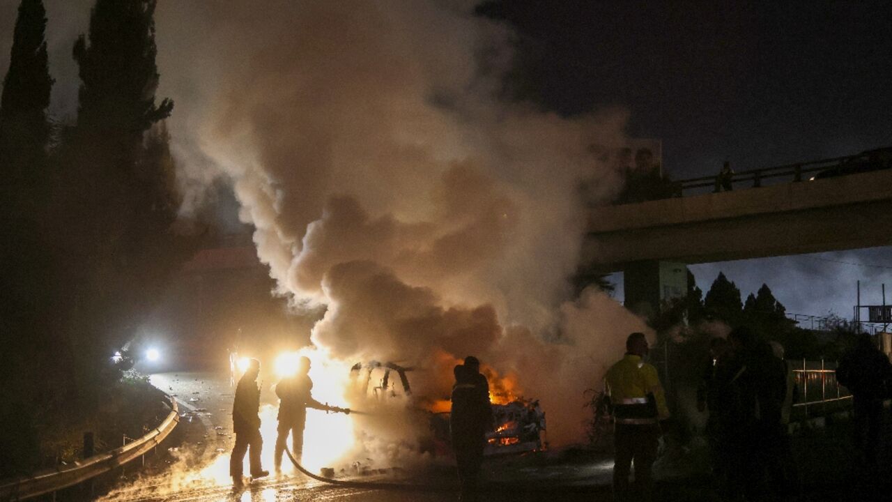 Firefighters extinguish a burning UNIFIL vehicle on the road leading to Beirut's international airport on Friday night