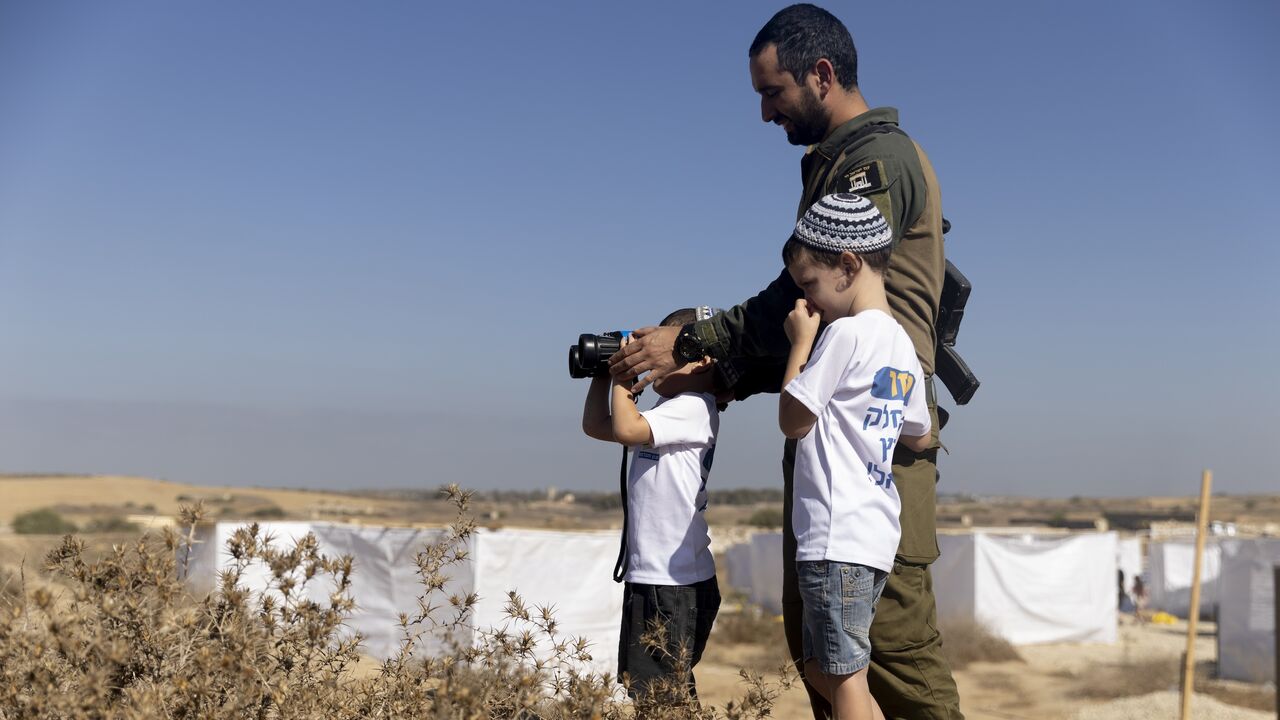 Israeli soldier and kids use binoculars during a Sukkoth gathering, calling for resettling Gaza with Jewish communities near the border with the Gaza Strip on Oct. 21, 2024 in Southern Border, Israel.