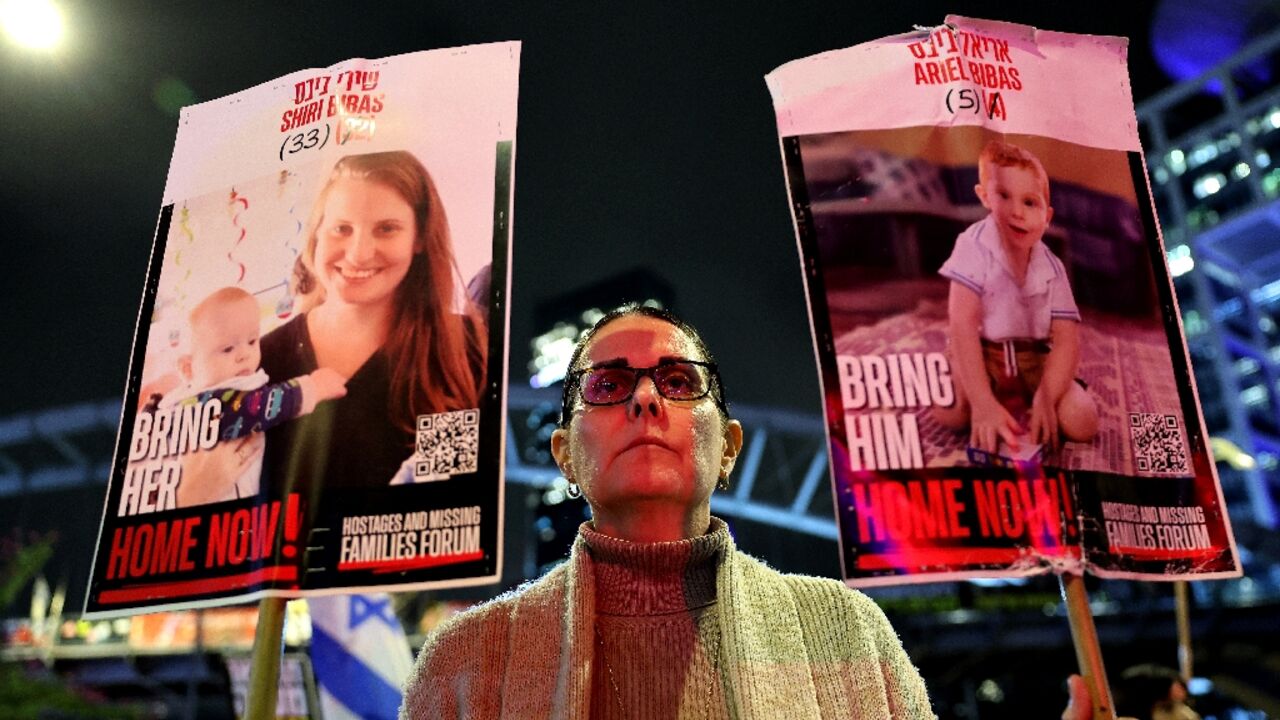 A demonstrator in Tel Aviv holds placards bearing pictures of members of the Bibas family