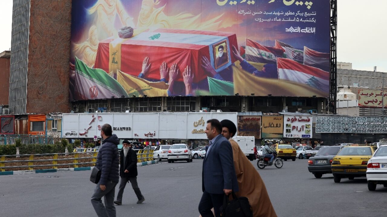 Iranians walk past an illustrated banner depicting the coffin of slain Lebanese Hezbollah leader Hassan Nasrallah, in Tehran Iranians walk past an illustrated banner depicting the coffin of slain Lebanese Hezbollah leader Hassan Nasrallah, in Tehran