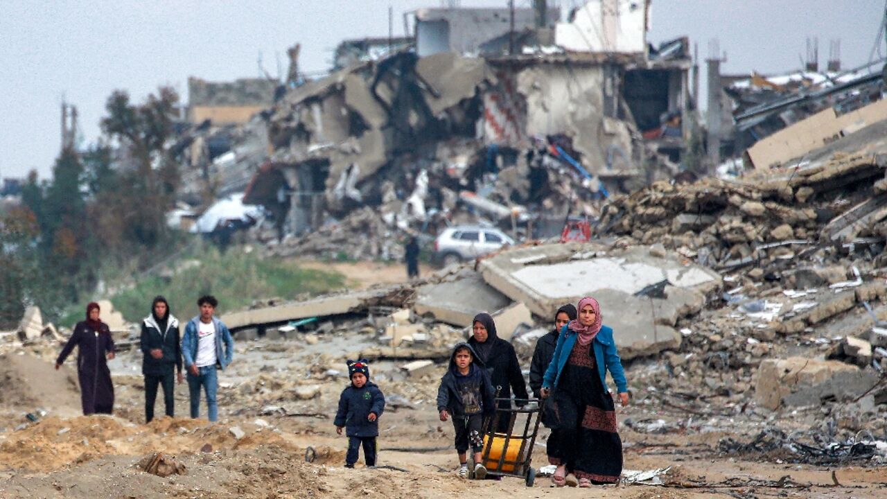 Women and children walk along a destroyed road in Beit Lahia, in the northern Gaza Strip