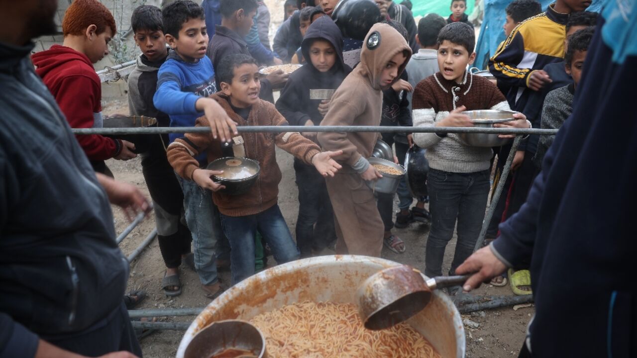 Palestinian children wait for a meal during food distribution at a charity kitchen at the Nuseirat refugee camp Palestinian children wait for a meal during food distribution at a charity kitchen at the Nuseirat refugee camp