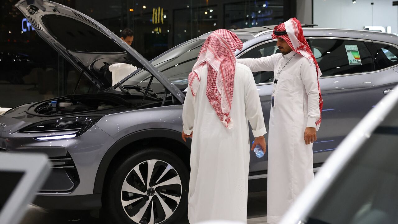Men inspect an electric car at a showroom in Riyadh, on June 8, 2024.