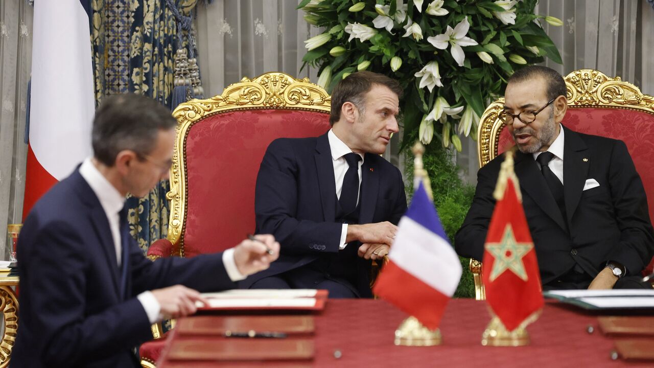 Morocco's king, Mohammed VI, speaks with France's president, Emmanuel Macron, as France's minister of the interior, Bruno Retailleau, and his counterpart from Morocco sign documents during their meeting in the Royal Palace in the capital, Rabat, on Oct. 28, 2024. 