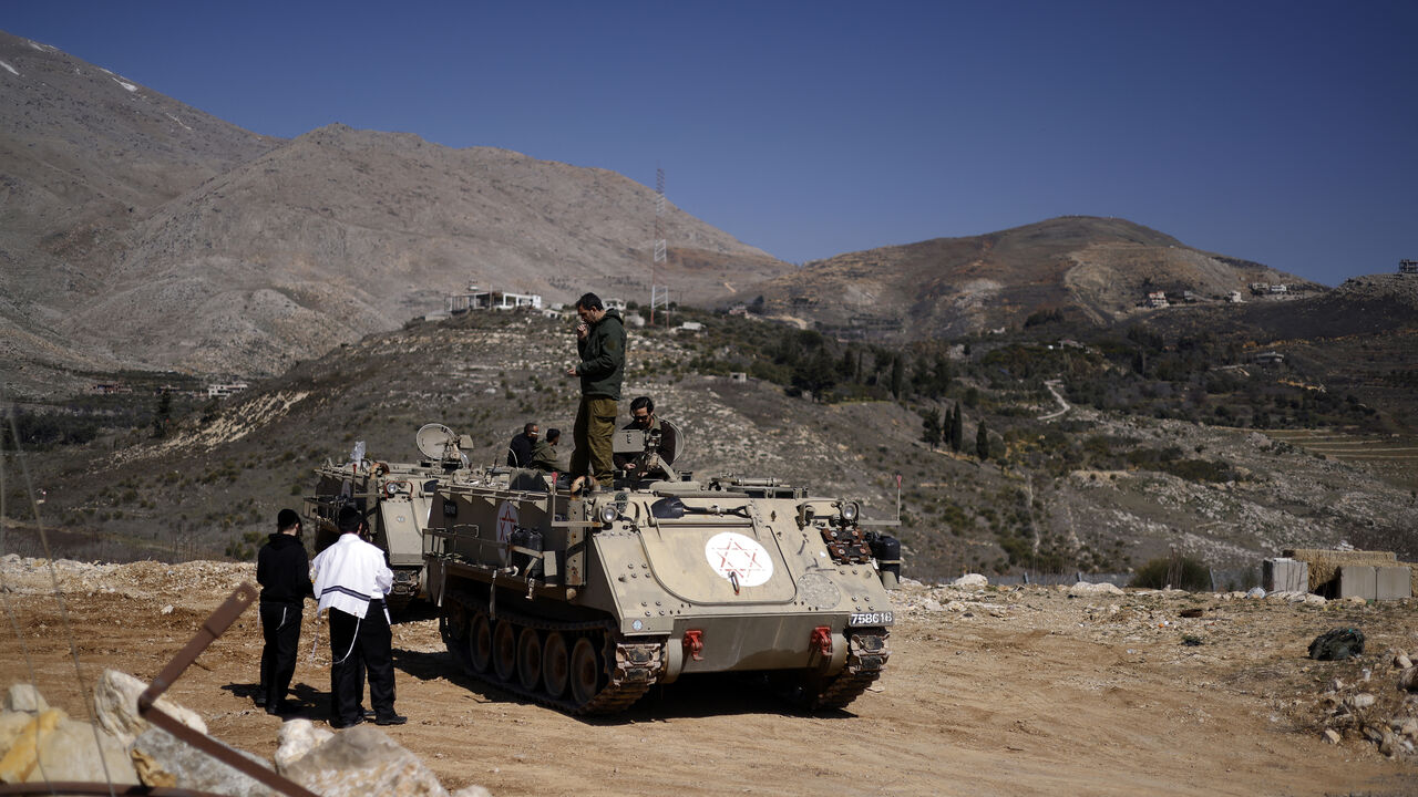 Ultraorthodox Jewish men speak to soldiers standing on an armored personnel carrier in the buffer zone that separates the Israeli-annexed Golan Heights and Syria, near the Druze village of Majdal Shams, Feb. 27, 2025.