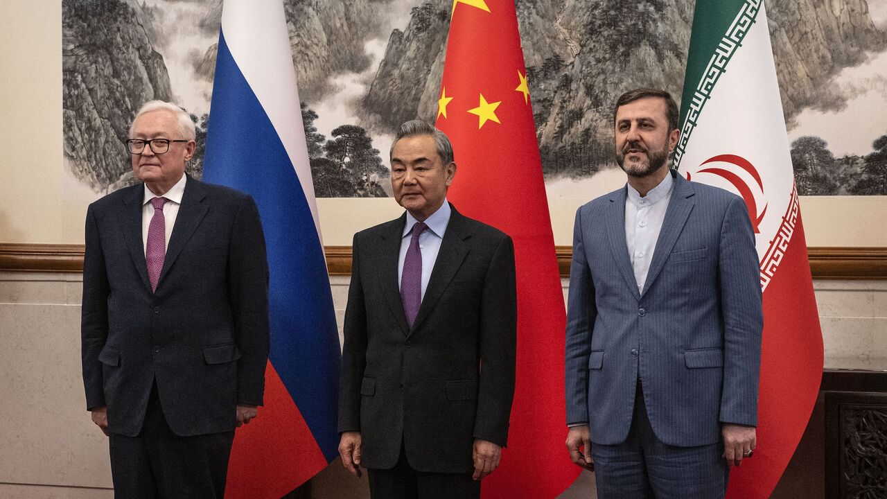 China's Foreign Minister Wang Yi (C) welcomes Russia's deputy foreign minister, Sergey Ryabkov (L), and Iran's deputy foreign minister, Kazeem Gharibabadi, before a meeting regarding the Iranian nuclear issue on March 14, 2025.