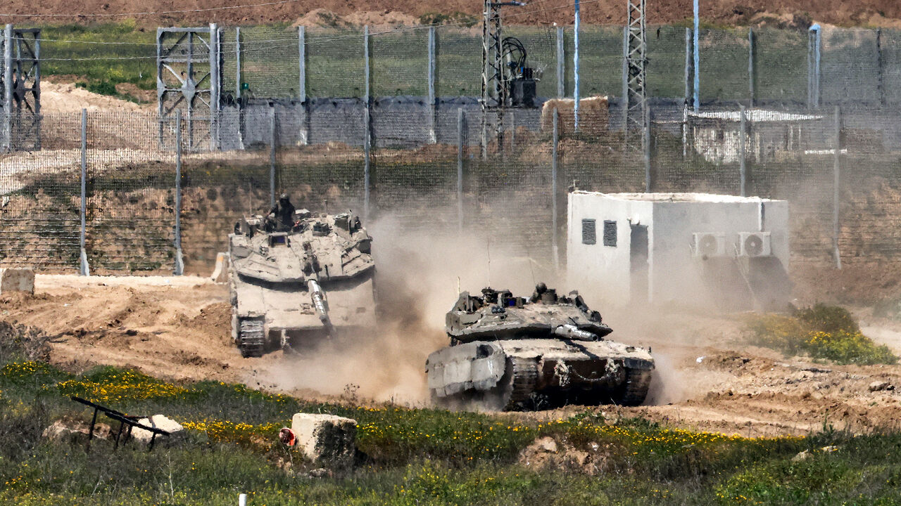 Israeli army Merkava main battle tanks move at a position in southern Israel along the border fence with the northern Gaza Strip on March 18, 2025.