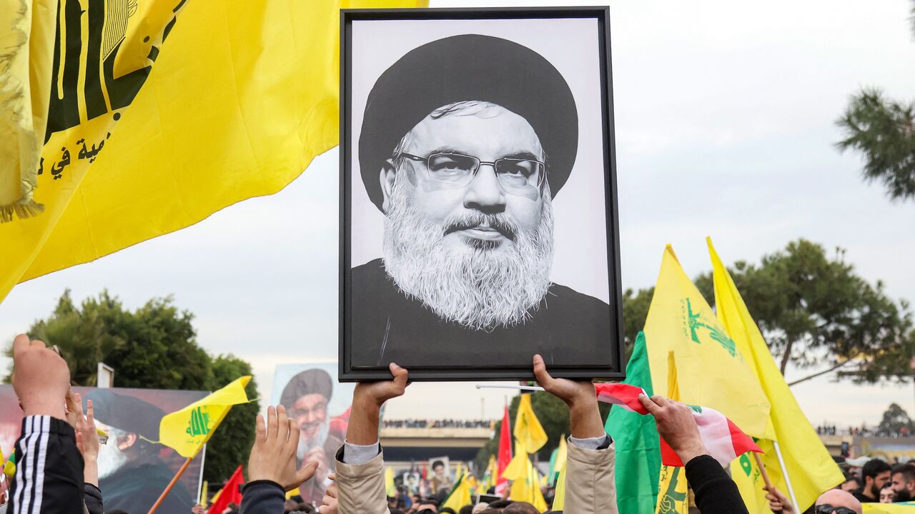 A protester holds a framed portrait of Hassan Nasrallah.