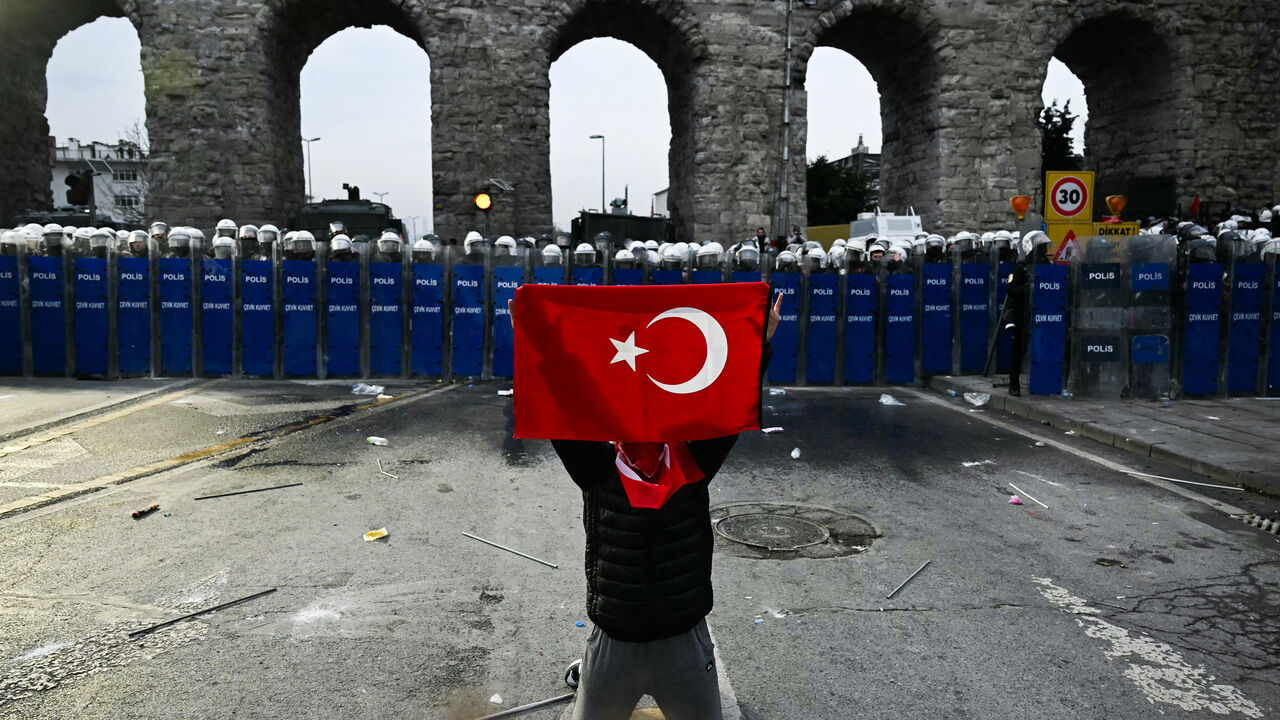 A protester holds a Turkish flag in front of police officers during a rally in support of Istanbul's arrested Mayor Ekrem Imamoglu, Istanbul, Turkey, March 23, 2025.
