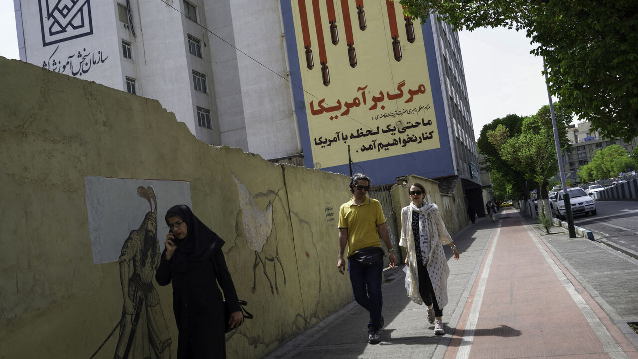 Iranians pass by the recently repainted, famous anti-American mural that depics the US flag with bombs and skulls in Tehran, Iran on April 10, 2025, two days before the first round of indirect nuclear negotiations with President Trump's administration hosted and mediated by Oman. (Photo by Mohammadali Najib / Middle East Images / Middle East Images via AFP) (Photo by MOHAMMADALI NAJIB/Middle East Images/AFP via Getty Images)