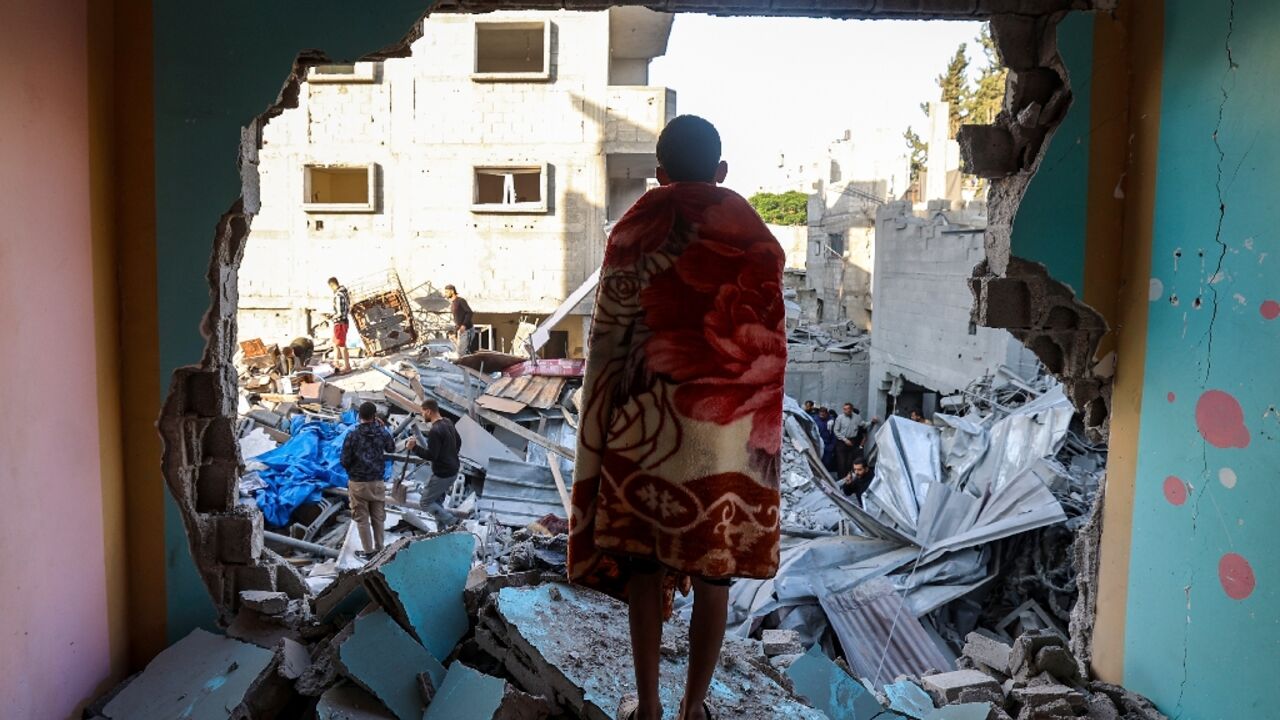 A youth draped in a blanket looks on as people look for survivors in the rubble of a building hit in an Israeli strike in the Bureij camp A youth draped in a blanket looks on as people look for survivors in the rubble of a building hit in an Israeli strike in the Bureij camp