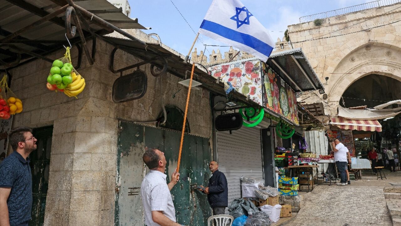 An Israeli flag is removed from above a Palestinian-owned shop in the wake of Jerusalem Day An Israeli flag is removed from above a Palestinian-owned shop in the wake of Jerusalem Day