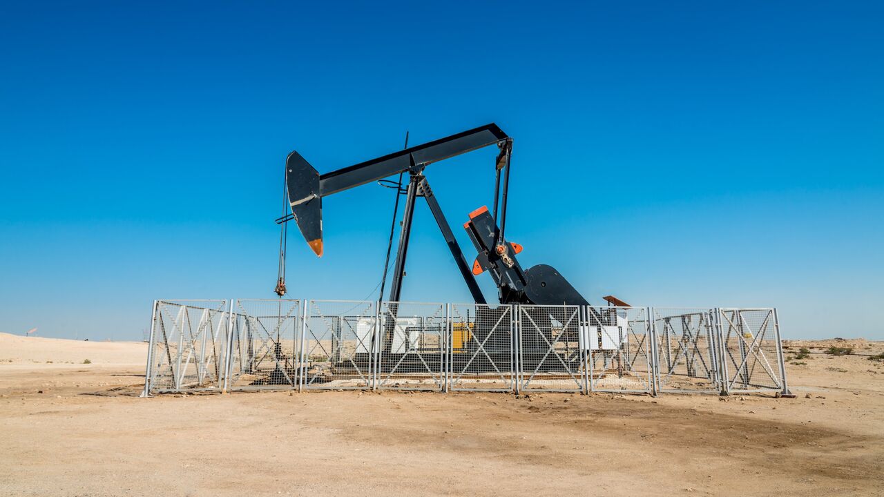 Nodding donkey rig pumping crude oil up from the ground of an oil field in the desert.
