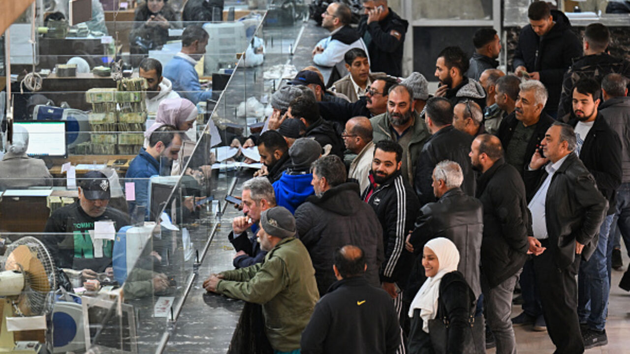 People queue in front of tellers at a commercial bank affiliated with Syria's central bank in Damascus on December 16, 2024. Governments worldwide are stepping up efforts to engage with Syria's new interim rulers, just over a week after Islamist-led rebels ousted president Bashar al-Assad, ending decades of brutal rule and civil war. (Photo by LOUAI BESHARA / AFP) (Photo by LOUAI BESHARA/AFP via Getty Images)