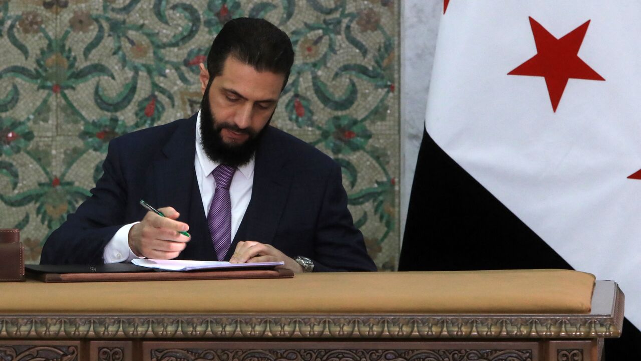 Syria's interim president, Ahmad al-Sharaa, signs the country's constitutional declaration, which will be enforced throughout a five-year transitional period, at the presidential palace in Damascus on March 13, 2025.
