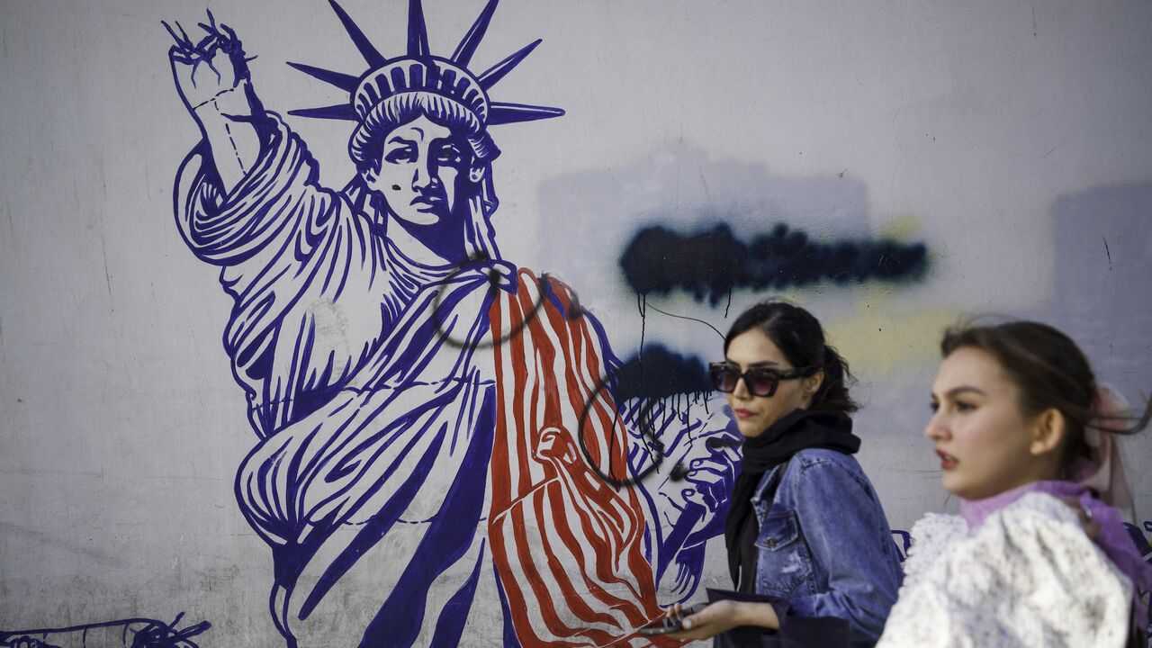 Iranians pass by the anti-American murals painted on the walls of the former embassy of the United States of America in Tehran, Iran on April 16, 2025.