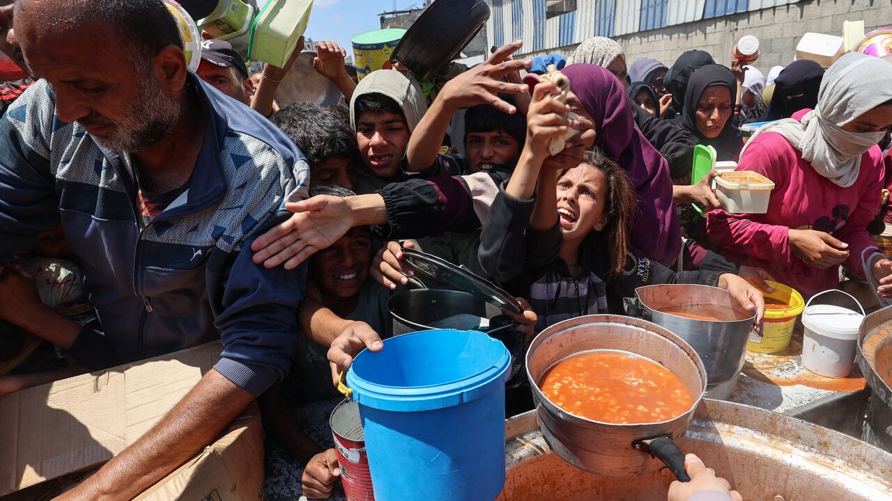 Displaced Palestinians scuffle for a portion of hot food at a charity kitchen at the Nuseirat refugee camp in the central Gaza Strip on May 5, 2025.