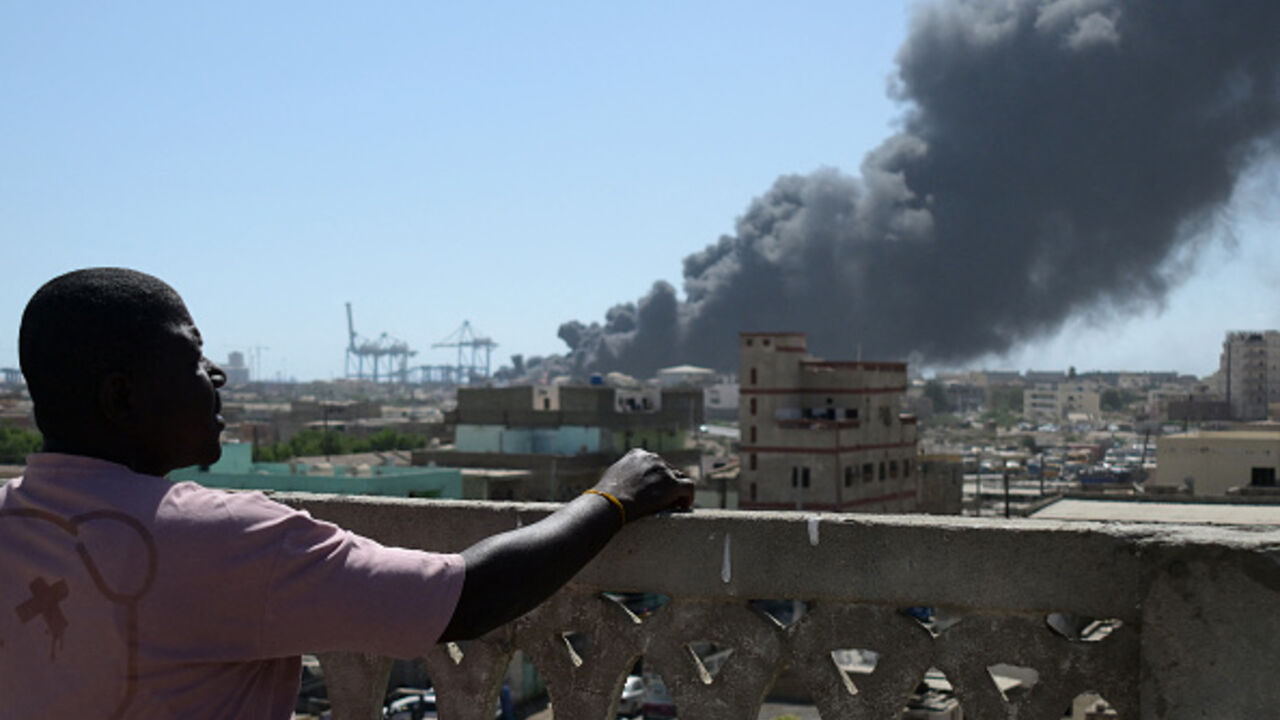 A man watches as smoke billows after a drone strike on the port of Port Sudan on May 6, 2025. Drones struck the airport and targeted an army base in Port Sudan on May 6, officials said, the third straight day the Sudanese army-aligned government's seat of power has come under attack. (Photo by AFP) (Photo by -/AFP via Getty Images)