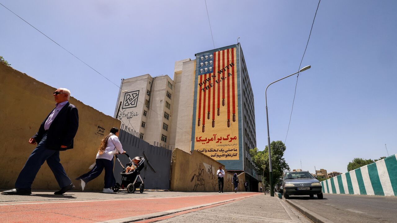 People walk near anti-US mural with the slogan "Down with the USA" and skulls replacing the stars on the flag, in Tehran, on May 20, 2025.