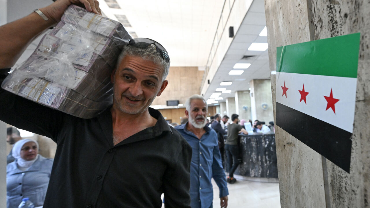 A man carrying a stash of Syrian pounds, leaves the central bank in Damascus on May 21, 2025.