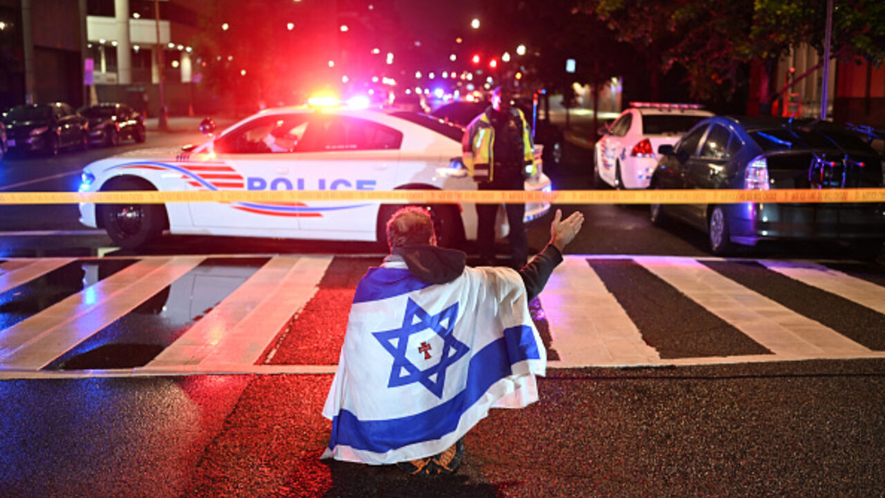 A man draped in the Israeli flag gestures as Metropolitan Police officers secure the area outside the Capital Jewish Museum following a shooting that left two people dead in Washington, DC, May 21, 2025. (AFP via Getty Images)