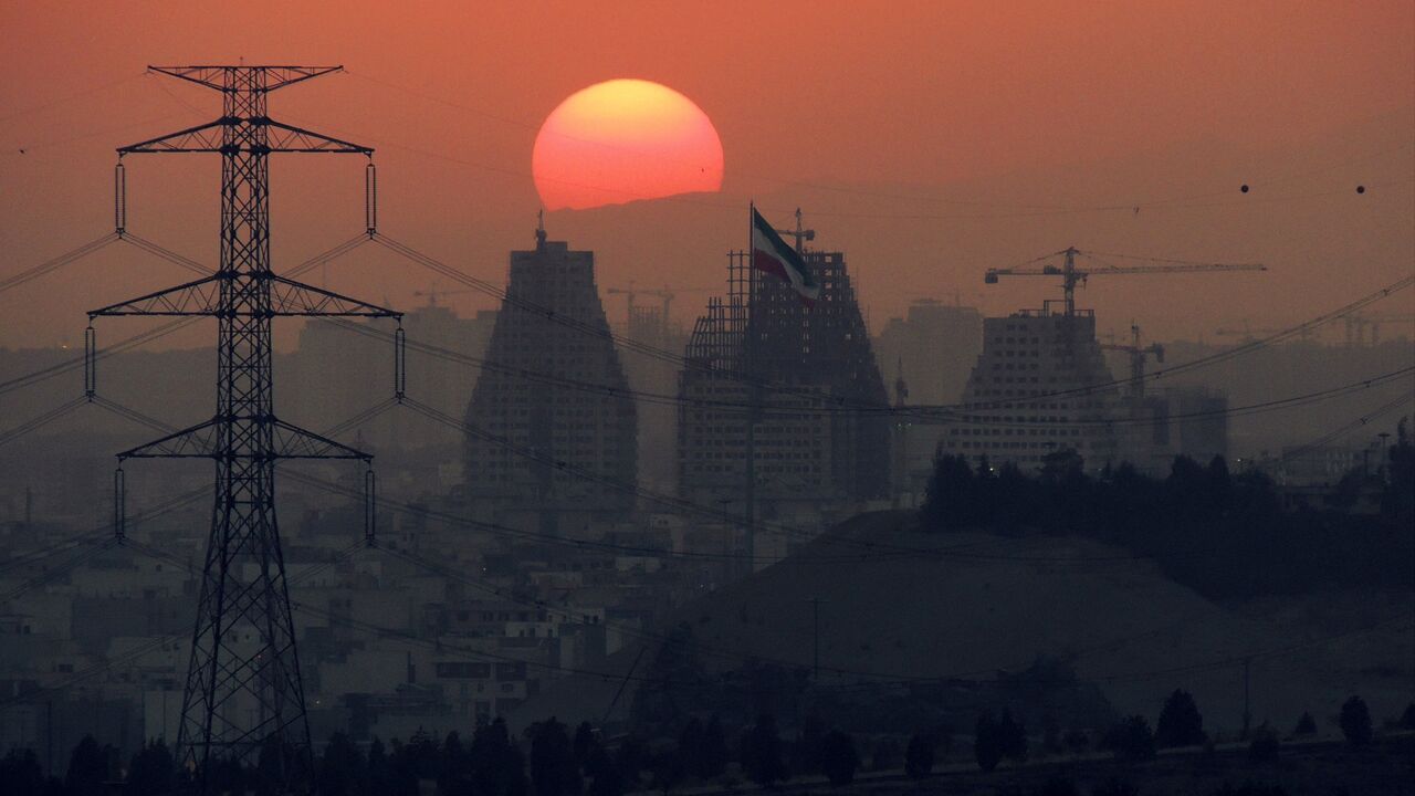 Sun setting at the back of large buildings under construction of Tehran at dusk.