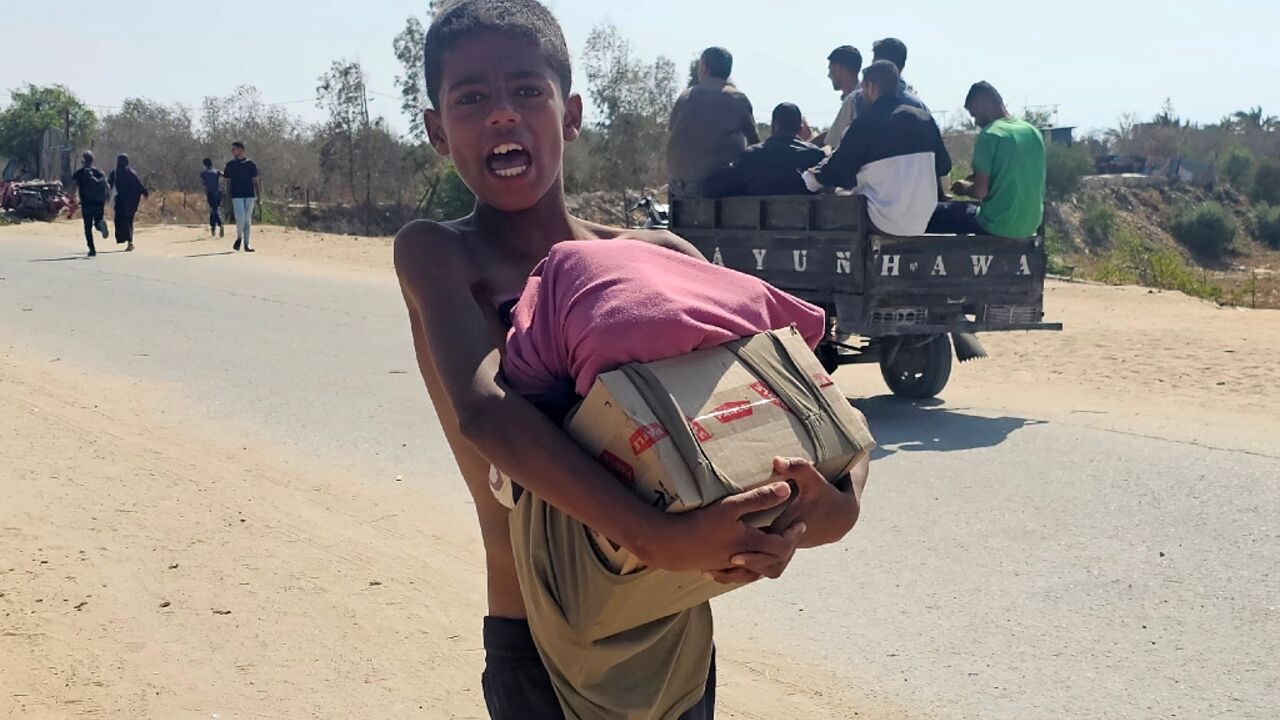 A boy walks with humanitarian aid relief packages as displaced Palestinians receive aid from a US-backed foundation in Rafah in southern Gaza A boy walks with humanitarian aid relief packages as displaced Palestinians receive aid from a US-backed foundation in Rafah in southern Gaza
