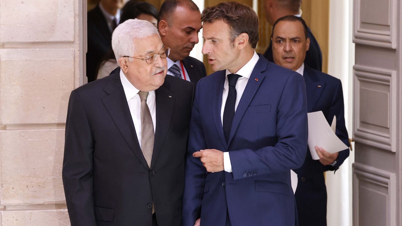 French President Emmanuel Macron (R) speaks with Palestinian President Mahmoud Abbas as they make their way to a meeting at the Elysee Presidential Palace in Paris on July 20, 2022.