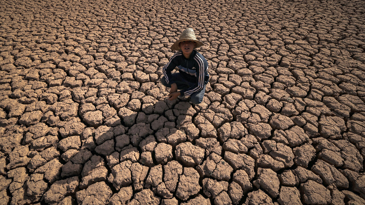 A child crouches over cracked earth at al-Massira dam in Ouled Essi Masseoud village, some 140 kilometres (85 miles) south from Morocco's economic capital Casablanca, on Aug. 8, 2022 amidst the country's worst drought in at least four decades.