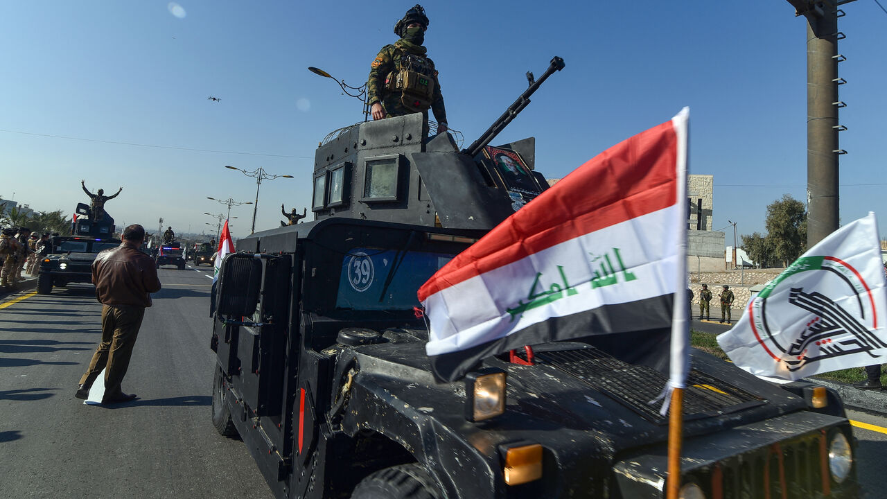 A military parade held by Iraq's army, Hashed al-Shaabi (Popular Mobilisation Forces), and the Police force drives on a highway during a ceremony marking the anniversary of the defeat of the Islamic State (IS) group, in the northern Iraqi city of Mosul on December 10, 2024. Iraq declared victory over fighters from the IS group at the end of 2017 after a three-year battle in which the jihadists had seized large swathes of the country. But jihadist cells still launch sporadic attacks against the army and poli