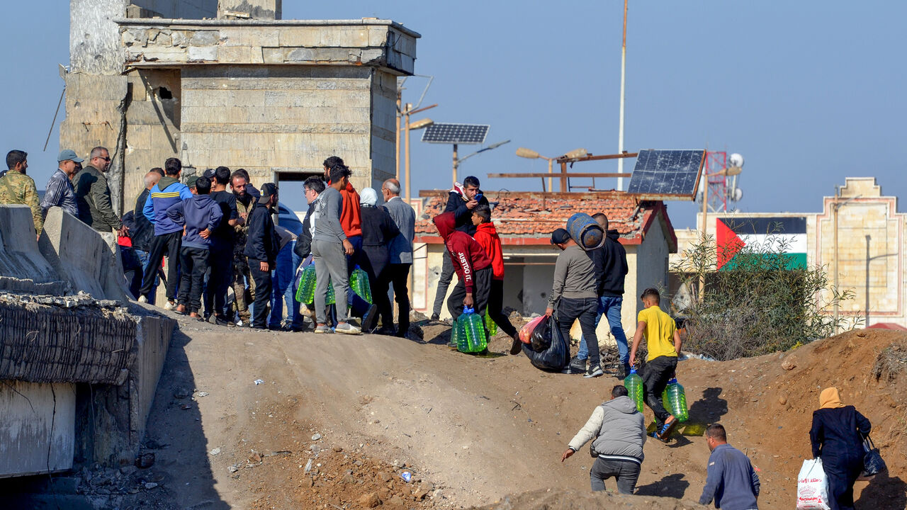 A photo taken from the Lebanese side of the northern border crossing of al-Arida shows Syrian rebel fighters assisting with the passage of Syrians back into their country, Dec. 10, 2024.