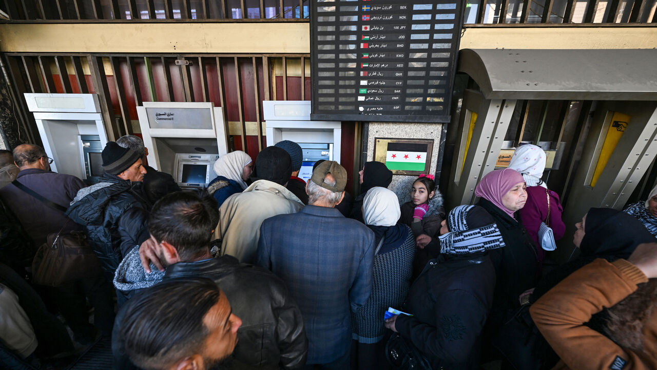 People queue to use ATM machines outside a bank in Damascus on Dec. 16, 2024. 