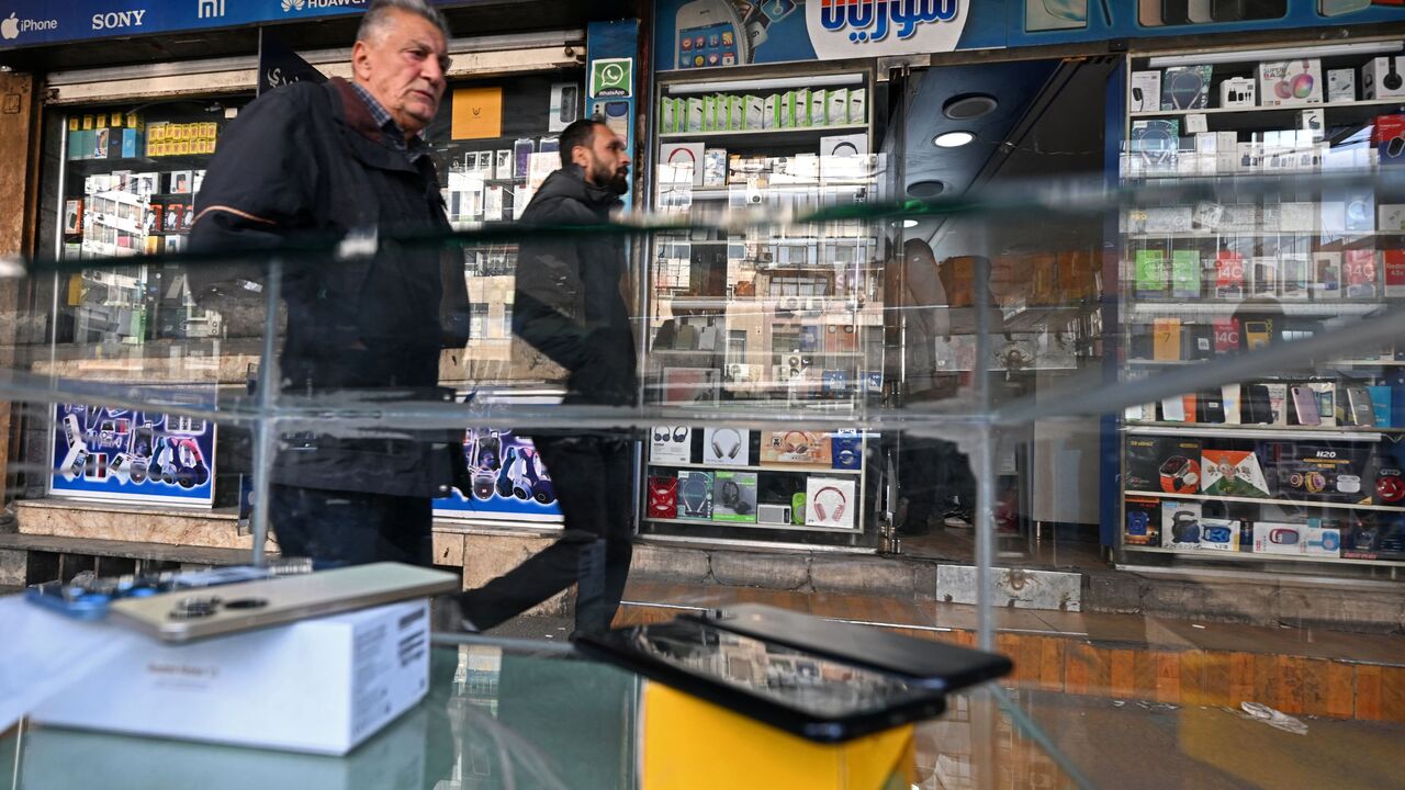 Men walk past shops selling mobile phones in the Damascus Tower market, which specializes in the smart phone business, in the Syrian capital on January 12, 2025.