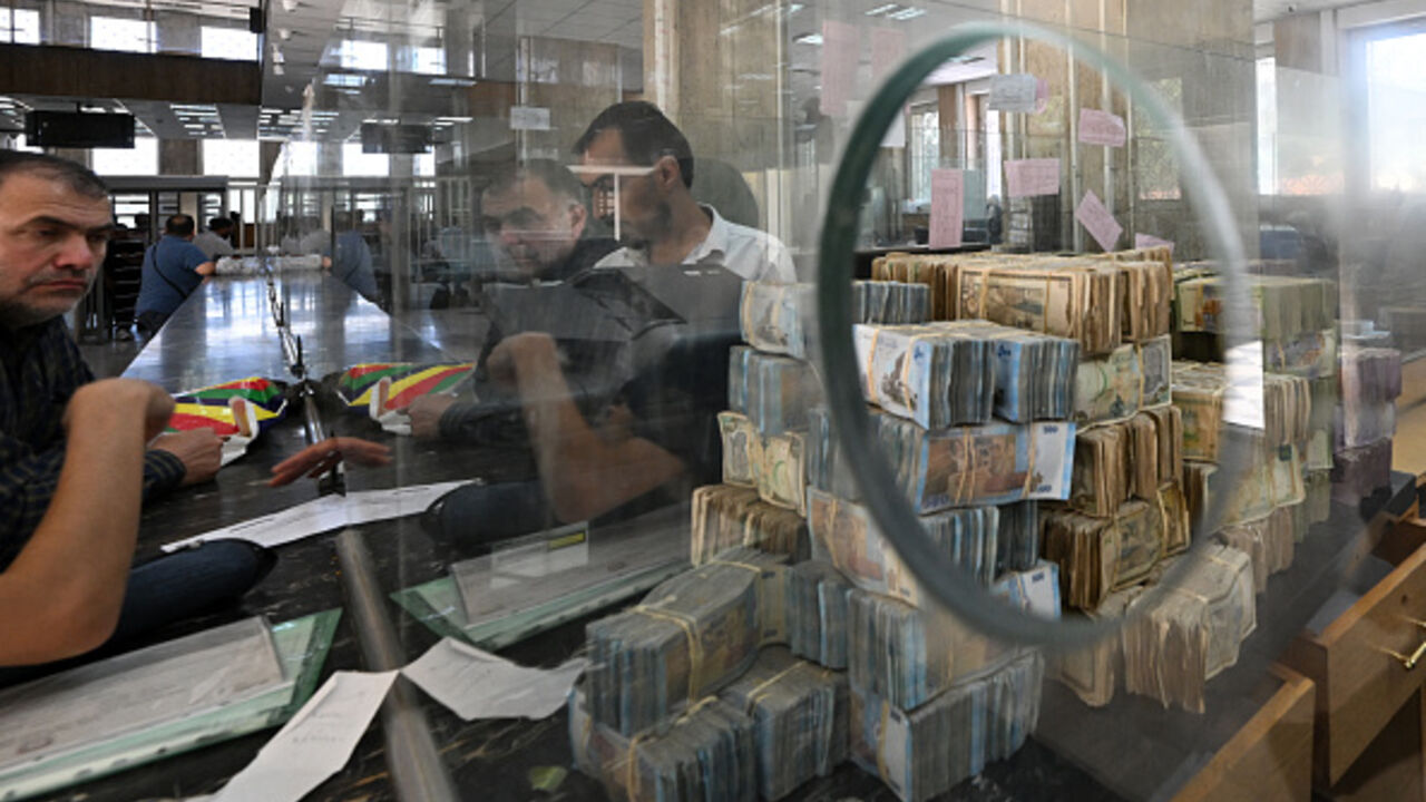 Bank notes of the local currency are piled up as people wait at the central bank in Damascus on May 21, 2025.