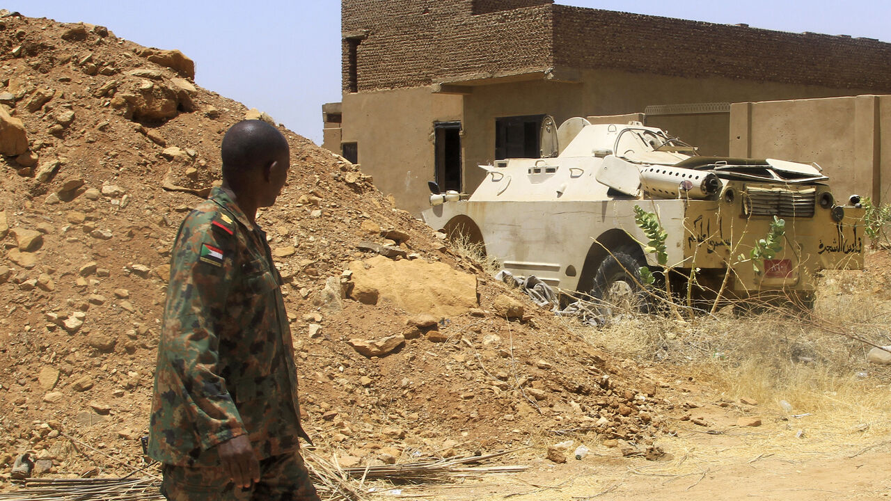 A Sudanese army officer walks near an armoured vehicle seized after their capture of a base used by the rival Rapid Support Forces (RSF) paramilitaries after the latter group evacuated from the Salha area of Omdurman, the twin-city of Sudan's capital, on May 26, 2025. Sudan, Africa's third largest country, has been ravaged by more than two years of war between the army and the RSF. The conflict has killed tens of thousands of people, displaced 13 million and created what the United Nations describes as the