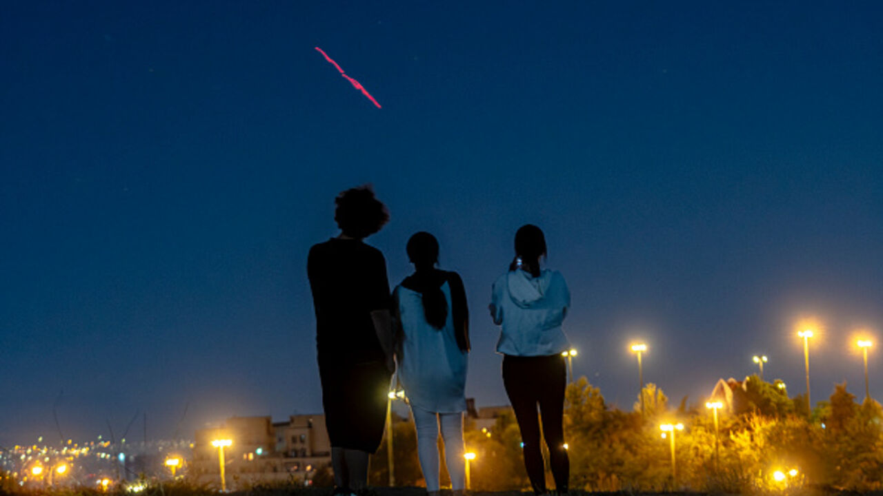 Israeli-Airstrikes-in-Tehran People gather on a hill to watch as Iran's air defense systems fire shots aimed at Israeli drones in the sky of Tehran, Iran, on June 14, 2025. Iran's foreign minister said the country would respond "decisively and proportionally" to a wave of attacks that Israel launched beginning in the early hours of June 13. The attacks targeted multiple military, scientific and residential locations, as well as senior government officials. (Photo by Khoshiran / Middle East Images via AFP) (